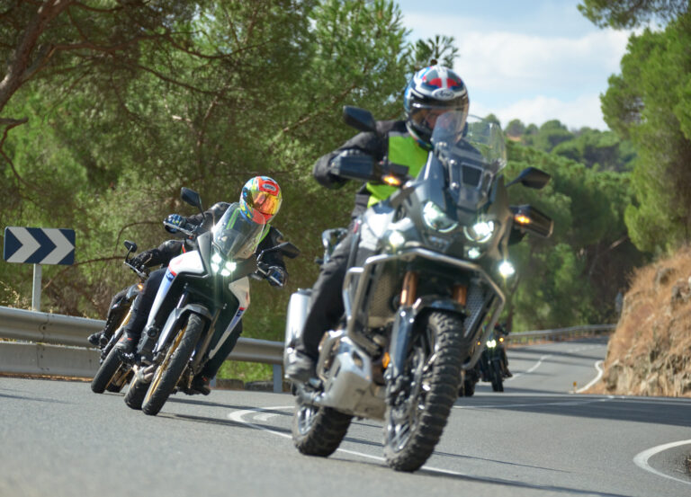 Grupo de motos en una carretera, con un instructor y alumnos realizando práctica de conducción.
